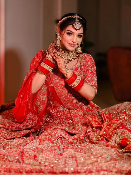 A confident bride looking directly at the camera, showcasing her full bridal look with a radiant smile.