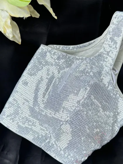 Why settle for one look when you can have endless style? This silver sequined blouse is perfect for a glam party night, instantly transforming your saree into a show-stopping outfit.