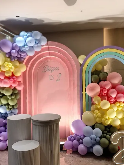 Another look at Diya's rainbow-themed second birthday. This angle shows the depth of the layered arches and the placement of the pedestals, which can be used for the cake or other decorative elements.