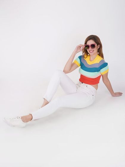A simple and clean e-commerce shot featuring a model in a colorful striped top and white jeans, perfect for catalogue listings.
