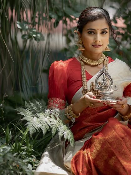 A beautiful portrait of our model holding a silver lamp, a symbol of light and prosperity. This image captures the essence of a traditional South Indian bride.