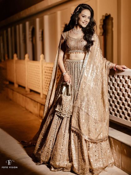 A full-length portrait of the bride in her shimmering gold lehenga, looking radiant and ready for her reception.