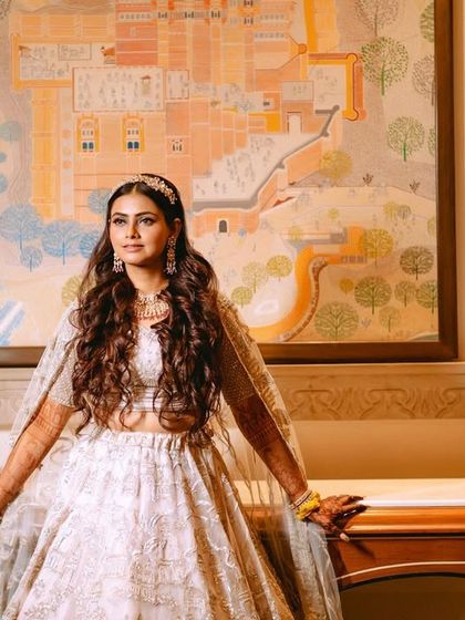 The bride posing against a piece of traditional Rajasthani art, blending her modern look with the heritage of the venue.