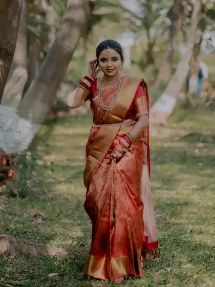A full-length outdoor portrait of the bride in her gorgeous red and gold saree.