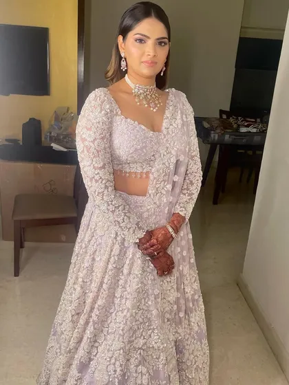 The full look is a dream. The soft, romantic makeup is the perfect complement to this intricately embroidered pastel lehenga.