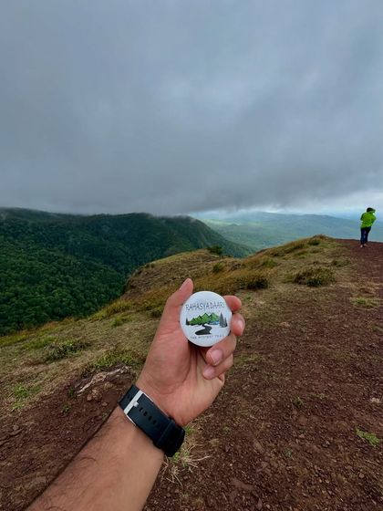 Our classic logo badge held up against the vast landscape of Chikmagalur.