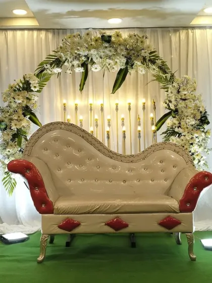 A closer view of the engagement stage with the white floral arch. The hanging candle-like lights in the background add a warm and romantic ambiance.