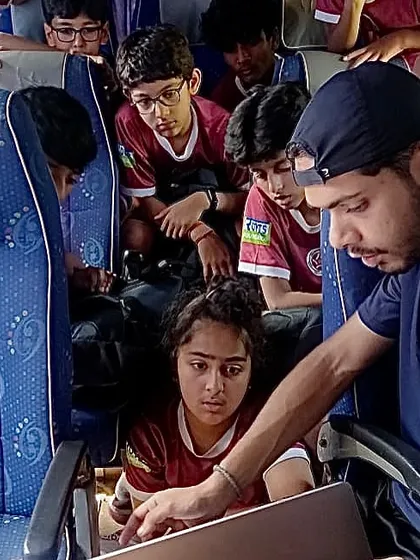 Learning doesn't stop on the pitch. Here, our coach uses a laptop on the team bus for video analysis, breaking down game footage with the players.