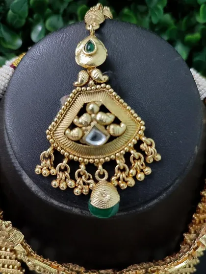 The maang tikka from this set, designed with the same antique gold finish to perfectly match the necklace.
