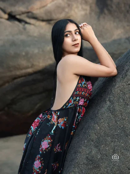 A close-up portrait of the model in the floral dress. The focus is on her expression and the beautiful, soft lighting of the beach environment.