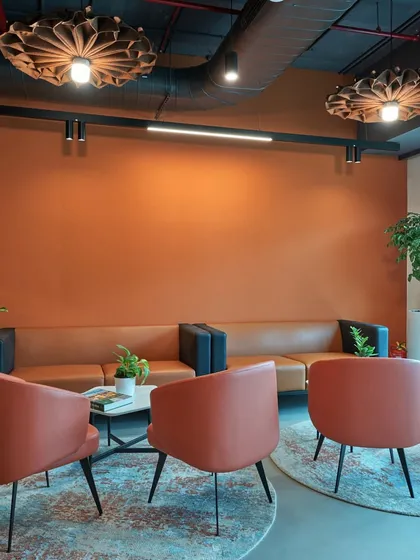 A lounge area with warm terracotta-colored walls and furniture. The patterned rug and unique ceiling lights add a touch of bohemian flair.