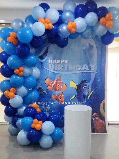 A Finding Nemo themed birthday decoration. The setup includes a blue balloon arch representing the ocean, framing a backdrop with Nemo and Dory.