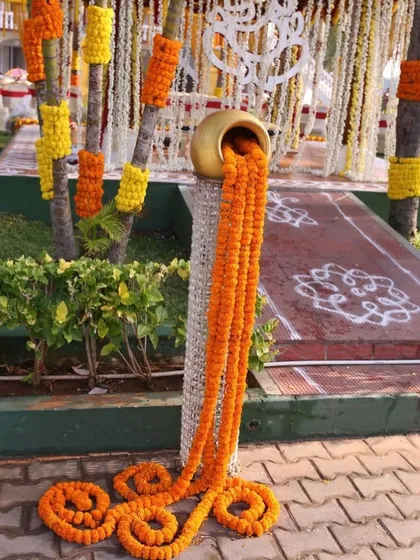 This is a popular decorative piece where marigold strings appear to flow out of a golden matka. It's a great way to add a traditional and eye-catching element to the event decor.