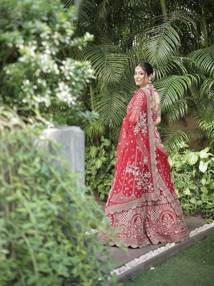 A full-length view of this bride in her stunning red lehenga. The makeup is balanced to complement the intricate outfit without being overpowering, perfect for wedding photography.