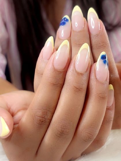 A beautiful combination of soft yellow French tips and delicate blue blooming flower art on almond-shaped extensions.