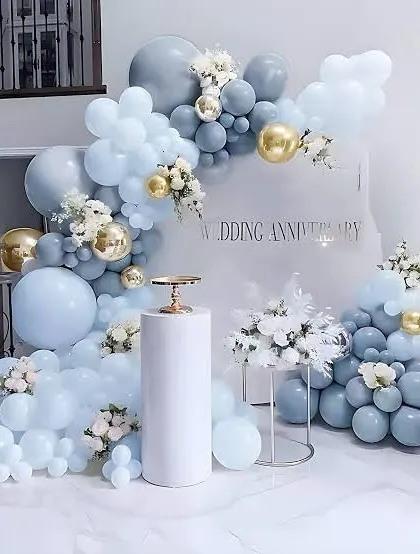 Celebrate your milestone with elegance. This sophisticated wedding anniversary decoration uses a soft blue, white, and gold color palette with a beautiful balloon arch and floral accents, creating a refined and memorable backdrop.