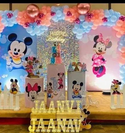A classic Mickey and Minnie Mouse theme for a first birthday. The pink and blue color scheme is perfect for a joint celebration, with character cutouts and a sequin backdrop.