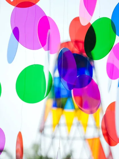 A creative decor element featuring colorful, translucent acrylic discs hanging from a frame, with the Coachella tower visible in the background.