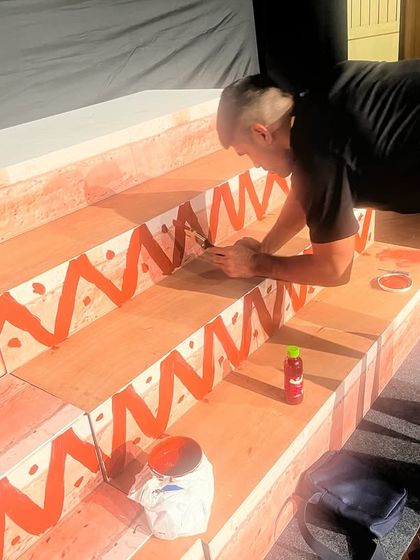 An artist carefully painting the details on our stage set. We believe every detail matters in creating a magical experience.