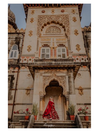 A solo portrait of the bride against the grand palace facade.