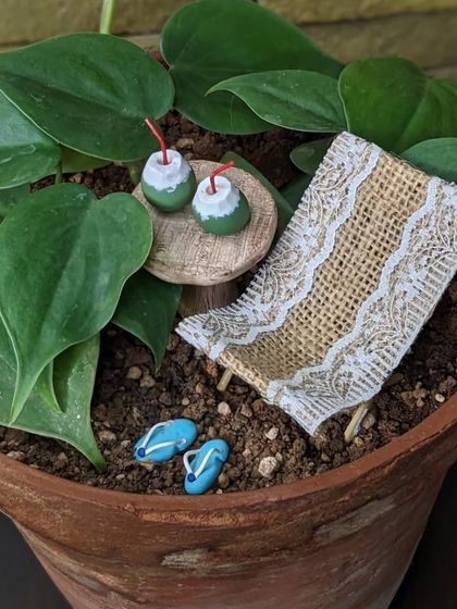 A closer look at the miniature beach setup. The tiny slippers, the textured chair, and the refreshing coconut drinks create a perfect little escape.