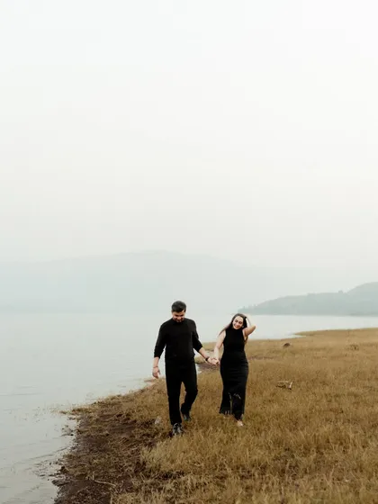 A minimalist shot of a couple walking by a serene lake. The misty, atmospheric quality of the light and landscape gives this photo a quiet and contemplative feel.