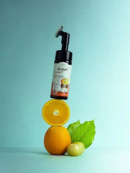 A playful balancing act with a Vitamin C face wash, an orange, and other fruits. This creative composition is fun, colorful, and visually communicates the product's key ingredient.