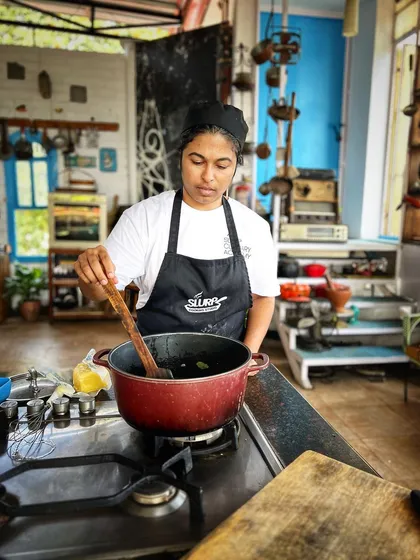 A student carefully stirs a pot, learning the importance of temperature control and patience in developing flavors.