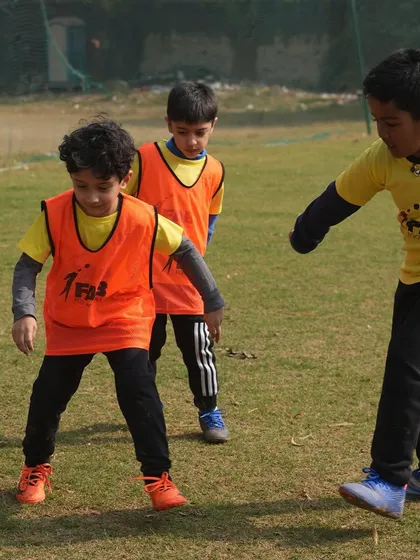 Two players in orange bibs during a drill. We believe talent without hard work is nothing, and our sessions are designed to combine both.