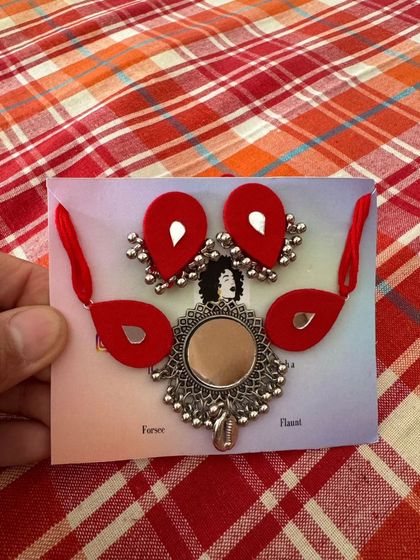 My classic mirror necklace sets are available in a range of colors like red, yellow, and black. They feature a large central mirror pendant with fabric accents and matching earrings.