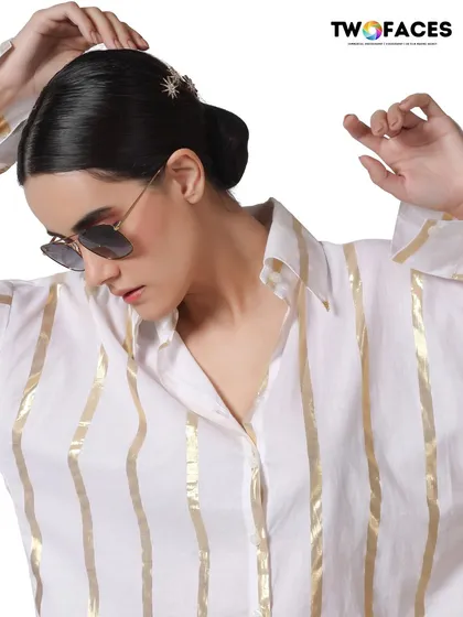 A model wearing a white and gold striped shirt with sunglasses. The clean, high-key lighting and stylish pose give this image a fresh, modern feel perfect for a contemporary brand.
