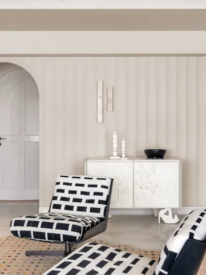 Another view of the living area in Apartment O2, showing the clean lines, arched doorway, and a focus on sculptural, artistic furniture pieces.