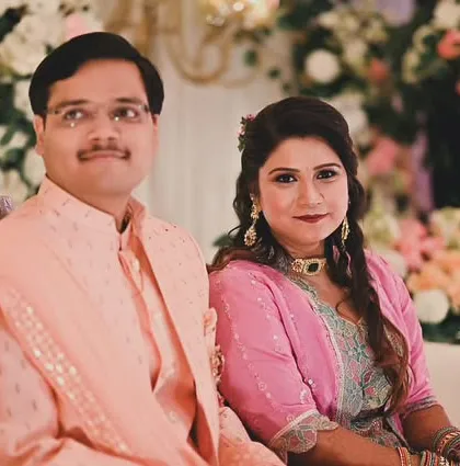 A classic portrait of the couple during their engagement ceremony. They are seated against a soft floral background, and our photography captures their poised and happy expressions.