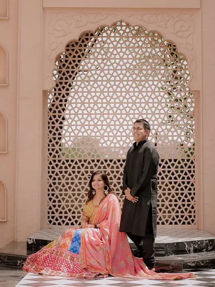 A formal portrait of the couple set against a stunning archway with intricate jali work. This type of shot has a timeless, royal feel perfect for a pre-wedding album.