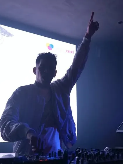 A silhouette shot against the bright VJ screen, raising a hand to the sky.