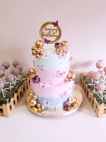 A dreamy pastel birthday cake surrounded by matching cake pops. This beautiful dessert spread, with its soft colours and gold accents, creates a stunning and cohesive party theme.