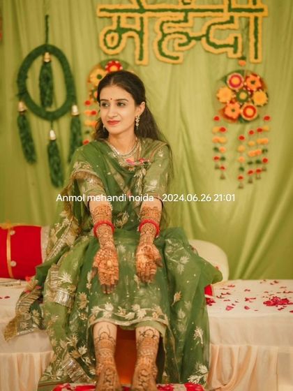 The bride seated gracefully, presenting her fully decorated hands and feet for a beautiful photo.