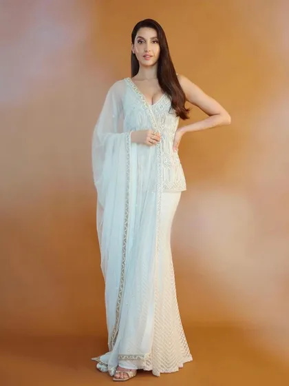 Nora Fatehi looks ethereal in this white peplum and sharara set by Ritika Mirchandani. This is a great example of fusion wear, blending traditional embroidery with a modern silhouette for a chic, celebratory look.
