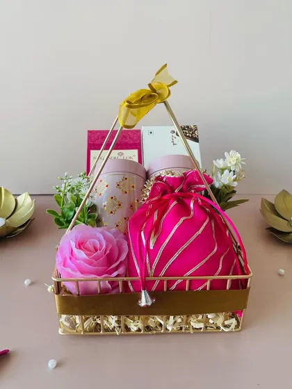 This elegant gold metal basket is curated with a pink theme. It includes a decorative tin, a pink potli, and a beautiful rose.
