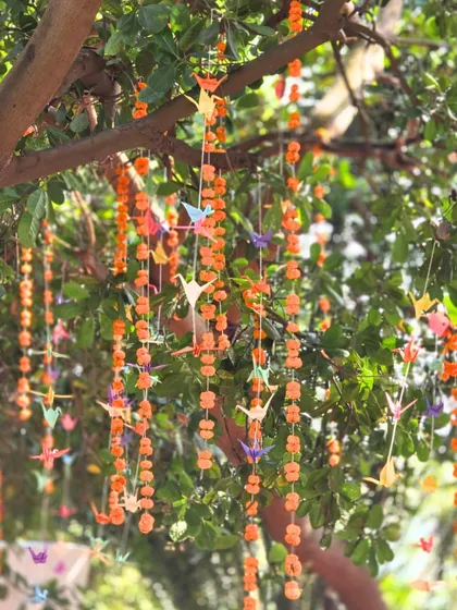 A unique decor detail: hanging garlands of marigolds interspersed with colorful origami birds, adding a touch of handmade artistry to the event.