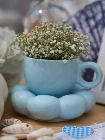 A close-up of the adorable baby's breath arrangement in a cloud-shaped teacup and saucer.