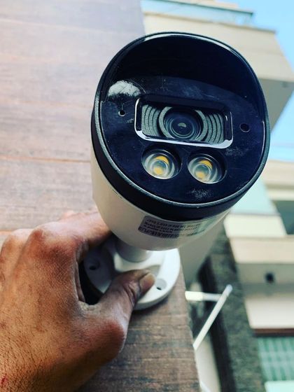 Holding a newly installed outdoor camera. Its sturdy build ensures it can withstand harsh weather conditions.