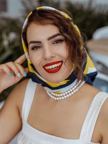 A bright, smiling portrait from the "dolce vita" series. The model's direct gaze and vibrant red lipstick create a captivating and joyful image.