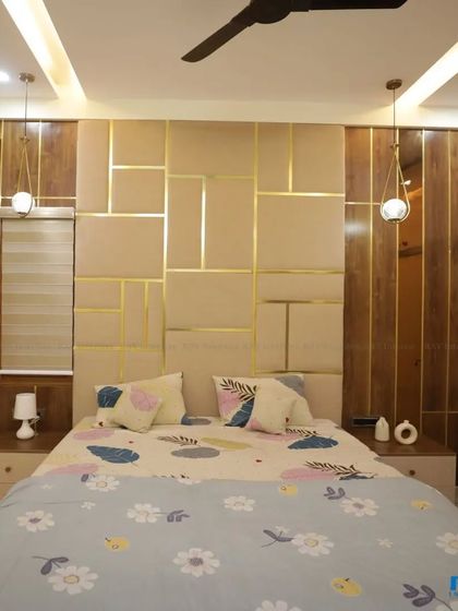 A bedroom with a padded, geometric-patterned headboard in beige and gold, creating a luxurious and comfortable feel.
