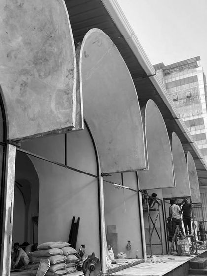 The "Vault's Up" structure during assembly on site. The pre-fabricated arched modules are being installed, creating a dramatic rhythm along the building's exterior.