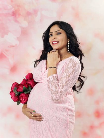 A glowing portrait of an expecting mother in a pink lace gown. Her happy expression and the soft lighting create a joyful and beautiful memory.