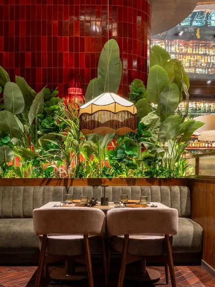 Another view of the interior at Hikki, where our red tiles provide a vibrant backdrop for the lush greenery and custom seating, contributing to the restaurant's unique and inviting atmosphere.