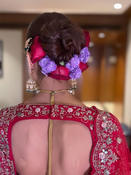 This bridal bun combines fresh red roses with delicate purple flowers, creating a unique and colorful floral arrangement that really stands out.