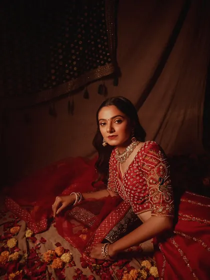 Another elegant portrait from the bridal series. The model's pose is graceful, and the lighting beautifully captures the details of her embroidered lehenga and jewelry.