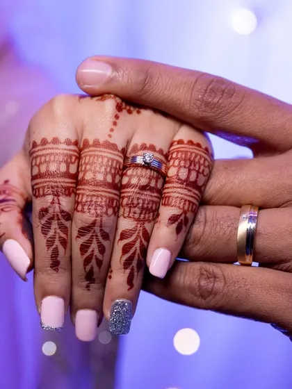 A close-up of the couple's hands, showing their wedding rings.